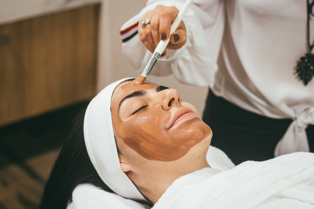 Terapeut natírá klientovi masku na obličej
